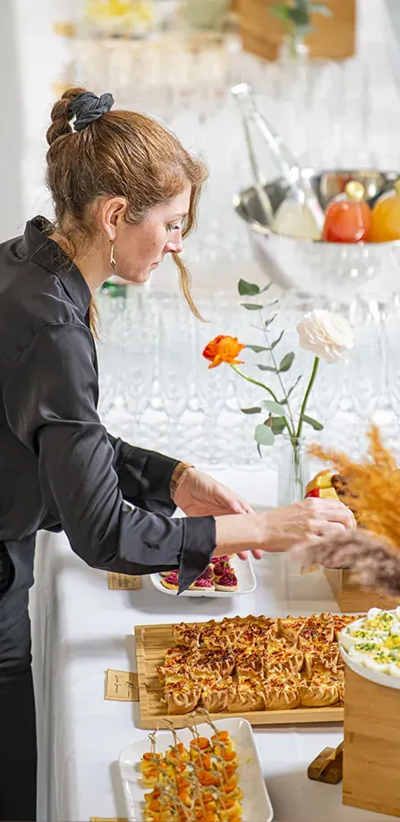 Une serveuse dresse un buffet de bouchées pour un cocktail d'entreprise