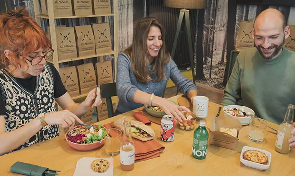 Trois collaborateurs déjeunent ensemble autour de plats du Moulin