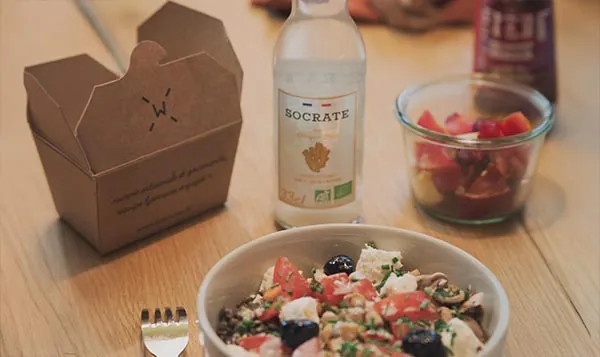 Bol de salade composée, boisson bio et boîte de dessert sur un bureau
