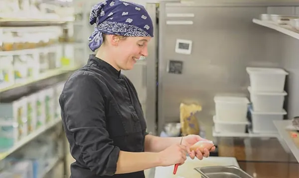 Une cuisinière du Moulin sourit en préparant un plat